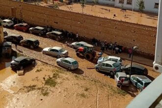 Un tractor ayuda a sacar coches atrapados en el lodo de la dana.