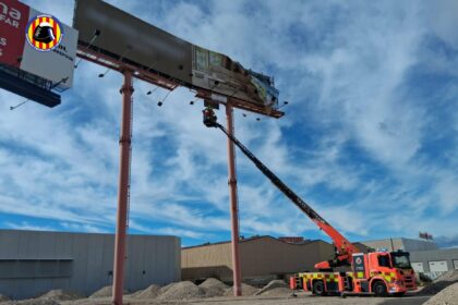Los bomberos intervienen en un panel publicitario afectado por los vientos huracanados.