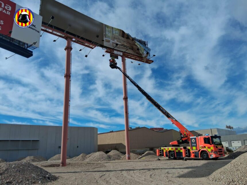 Los bomberos intervienen en un panel publicitario afectado por los vientos huracanados.