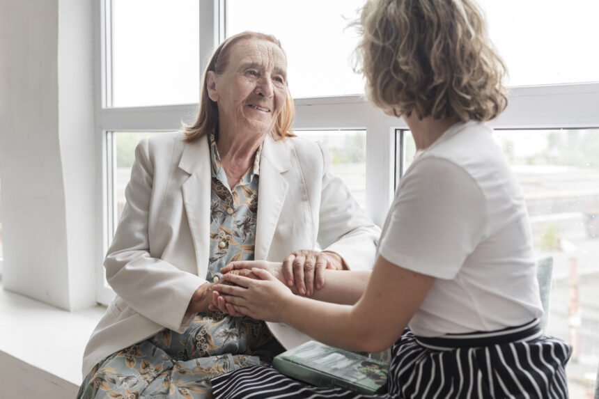 portrait senior woman holding her grand daughter s hand while sitting window sill