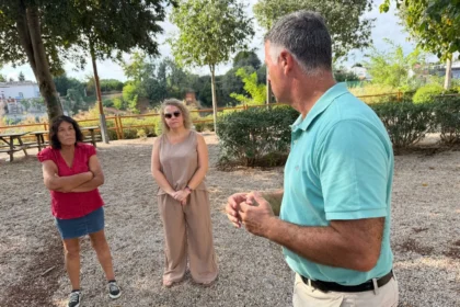 Tres personas conversan en una zona arbolada de la urbanización El Pantano, en Torrent