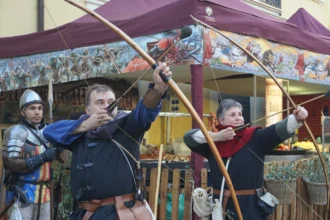 Arqueros con arco largo y un soldado con armadura, caracterizados de época, en el Mercado Medieval de Manises