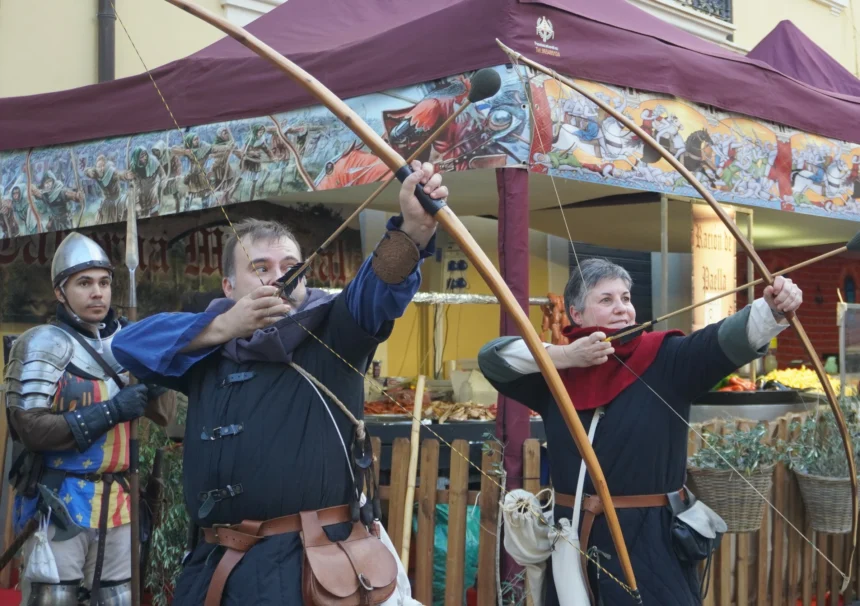 Arqueros con arco largo y un soldado con armadura, caracterizados de época, en el Mercado Medieval de Manises