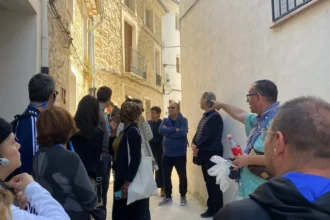 Grupo de personas escucha a un guía en una calle estrecha de Alpatró durante una visita guiada