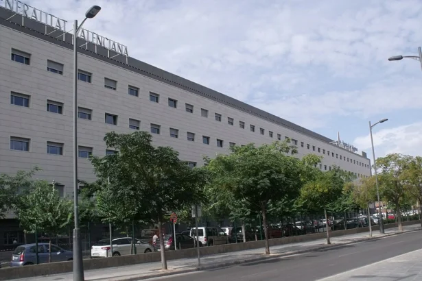 Fachada del edificio del Hospital de Manises, sede del departamento de salud, con árboles en la acera