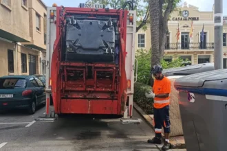 Operario de SAV junto a un camión de recogida de residuos en una calle de La Pobla de Farnals