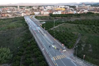 Vista aérea del puente de la CV-560 sobre el río Sellent entre Càrcer y Cotes, con operarios trabajando en la calzada