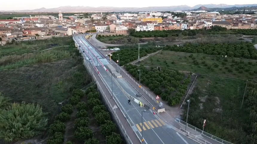 Vista aérea del puente de la CV-560 sobre el río Sellent entre Càrcer y Cotes, con operarios trabajando en la calzada