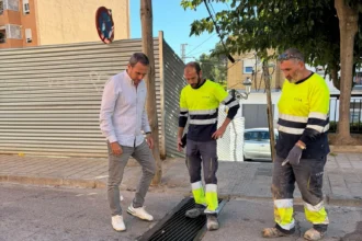 Operarios y un responsable municipal revisan un imbornal en una calle de Chiva