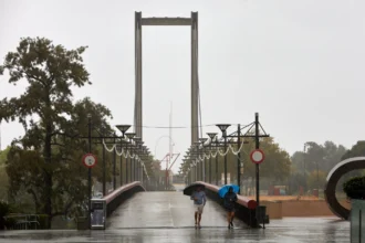 Dos personas con paraguas cruzan una pasarela de Gandia bajo la lluvia