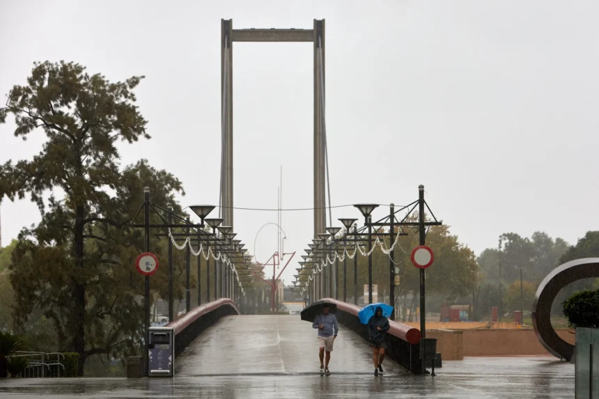 Dos personas con paraguas cruzan una pasarela de Gandia bajo la lluvia