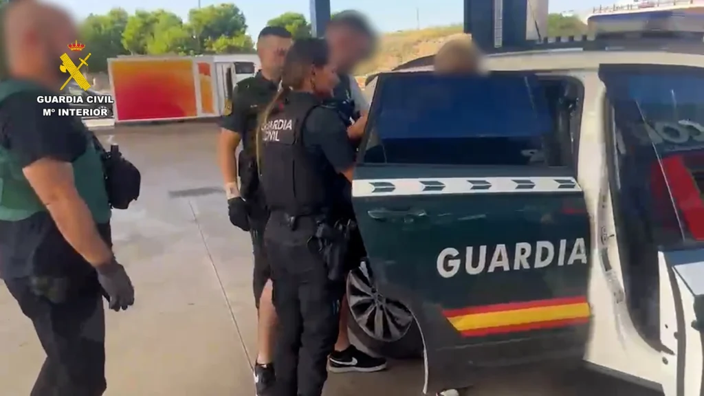 Agentes de la Guardia Civil junto a un vehículo oficial en una gasolinera durante la detención