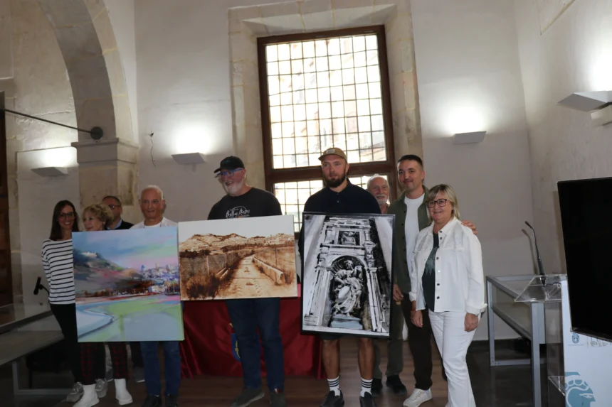 Participantes y autoridades posan con tres obras del concurso de pintura rápida «Pintor Josep Manaut» en Llíria
