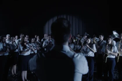 Una banda de música toca ante su director, de espaldas, en una escena de la campaña del pasodoble ‘Cervezas El Turia’