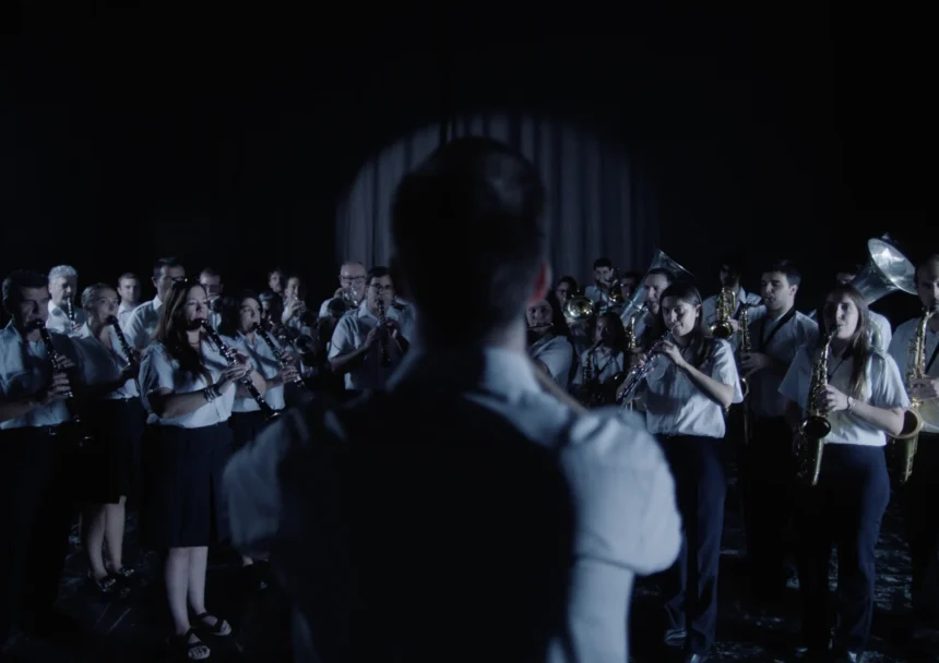 Una banda de música toca ante su director, de espaldas, en una escena de la campaña del pasodoble ‘Cervezas El Turia’