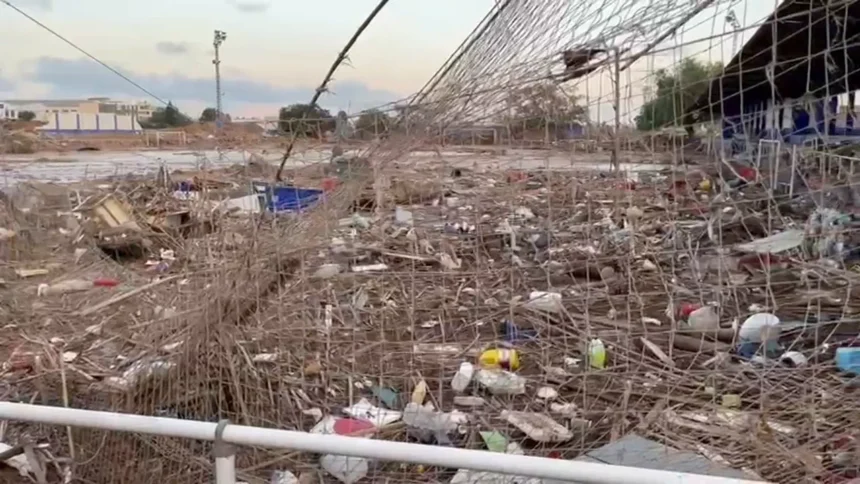 Estado del campo de fútbol El Palleter de Paiporta tras la dana de 2024, con la valla y el césped cubiertos de restos