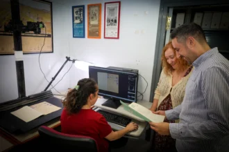 Tres personas revisan documentos junto a un escáner de digitalización en el Archivo Histórico Municipal de Torrent