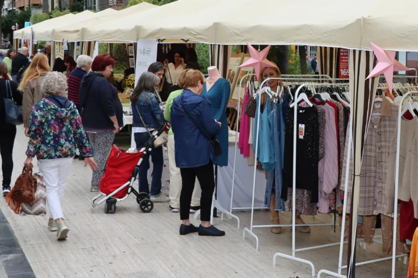 Visitantes ante puestos de ropa de una feria de comercio al aire libre