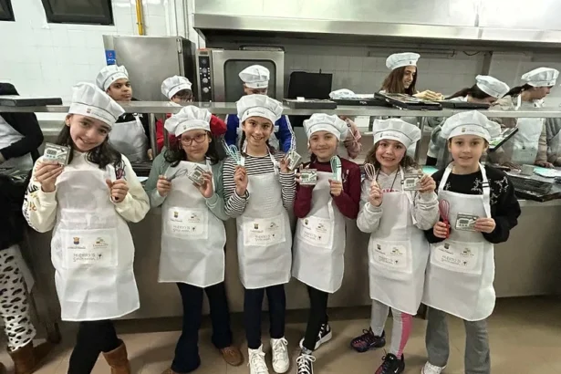 Niñas con delantal y gorro de cocinero muestran sus diplomas en la cocina de Xef Junior