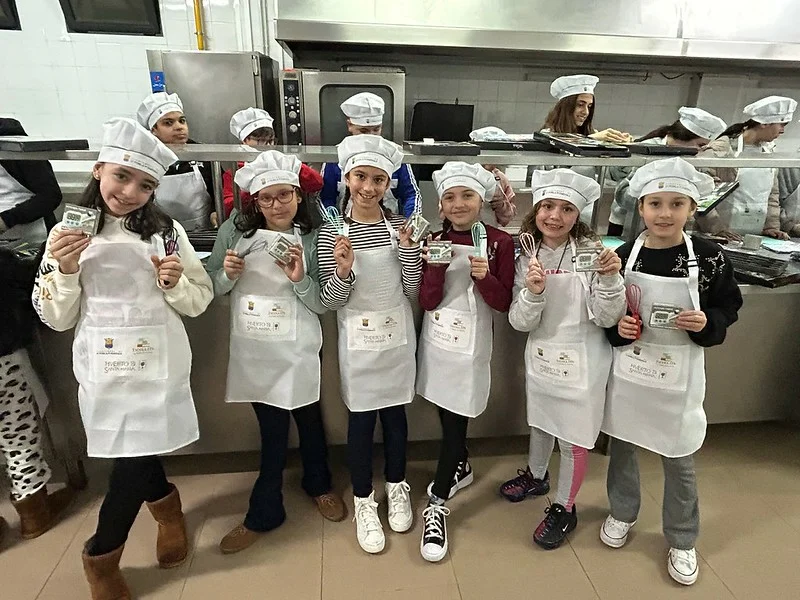 Niñas con delantal y gorro de cocinero muestran sus diplomas en la cocina de Xef Junior